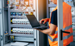 electrician with laptop near wires