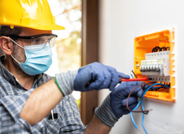 rewire specialist electrician with mask working on electrical socket