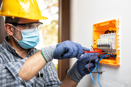 rewire specialist electrician with mask working on electrical socket