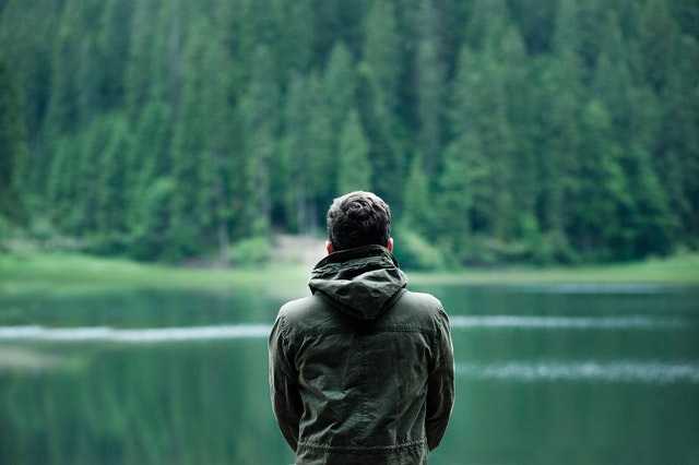 man staring into lake