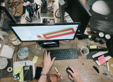 person using a computer with a messy desk