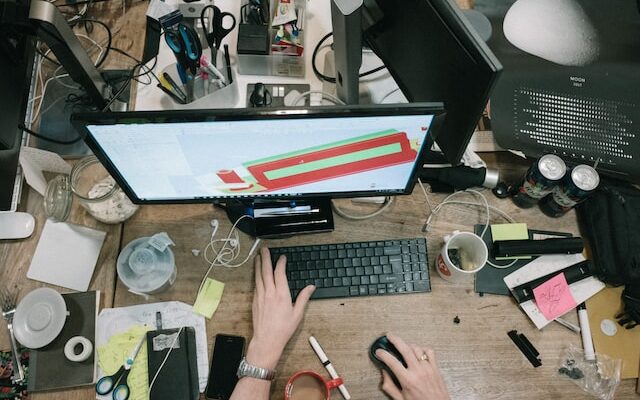 person using a computer with a messy desk